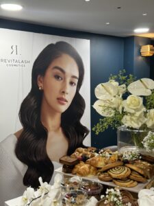 RevitaLash poster with woman and breakfast pastry selection 