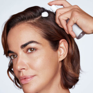 Woman spraying foam in her hair